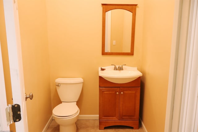 half bath with vanity, tile patterned flooring, toilet, and baseboards