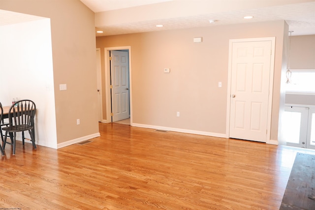 empty room with light wood-style floors, visible vents, and baseboards