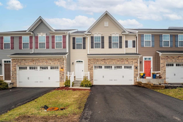 multi unit property with a garage, stone siding, and driveway