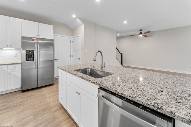 kitchen featuring ceiling fan, stainless steel appliances, a sink, white cabinets, and light wood-style floors