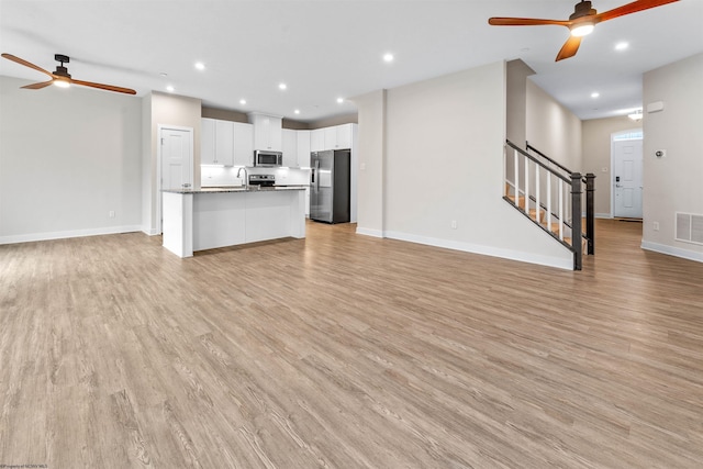 unfurnished living room featuring recessed lighting, visible vents, light wood finished floors, and stairs