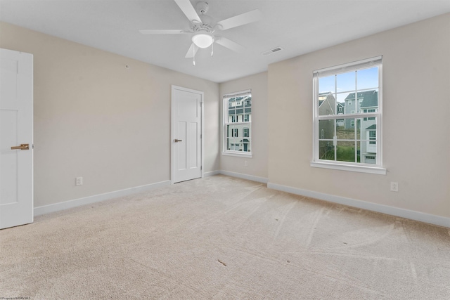 empty room featuring ceiling fan, carpet flooring, visible vents, and baseboards