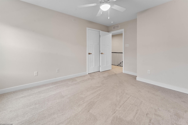 carpeted empty room featuring visible vents, ceiling fan, and baseboards