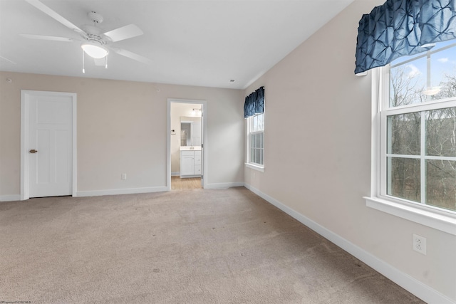 unfurnished bedroom with light colored carpet, ensuite bath, and baseboards