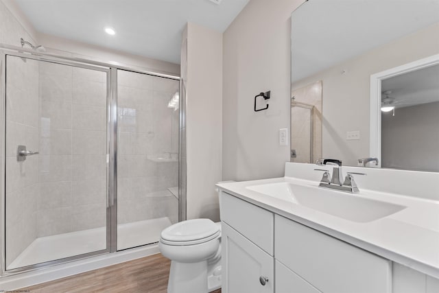 bathroom featuring a stall shower, vanity, toilet, and wood finished floors