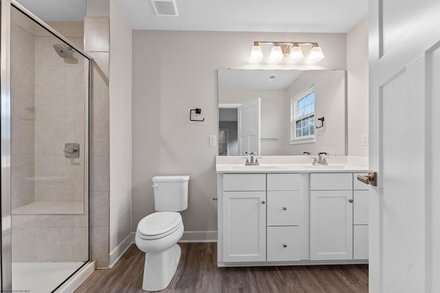 bathroom featuring visible vents, toilet, a stall shower, wood finished floors, and baseboards