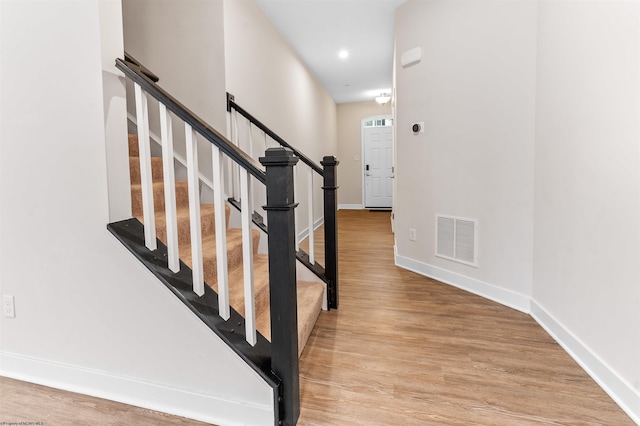 staircase featuring baseboards, visible vents, wood finished floors, and recessed lighting