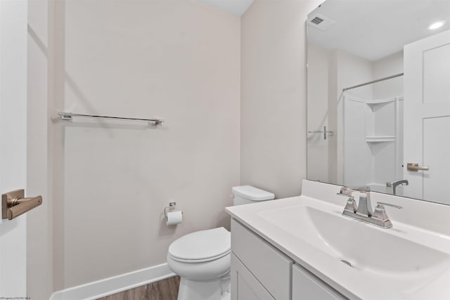 bathroom featuring visible vents, toilet, vanity, wood finished floors, and baseboards