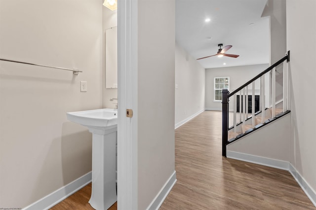 bathroom featuring a sink, ceiling fan, baseboards, and wood finished floors