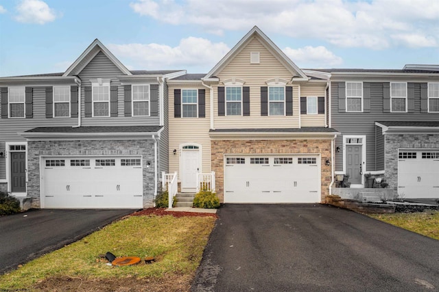 townhome / multi-family property featuring an attached garage, stone siding, and aphalt driveway