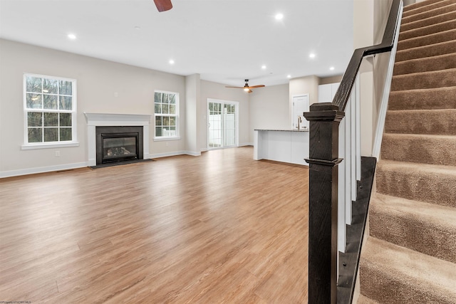 unfurnished living room featuring stairway, recessed lighting, ceiling fan, and light wood-style flooring