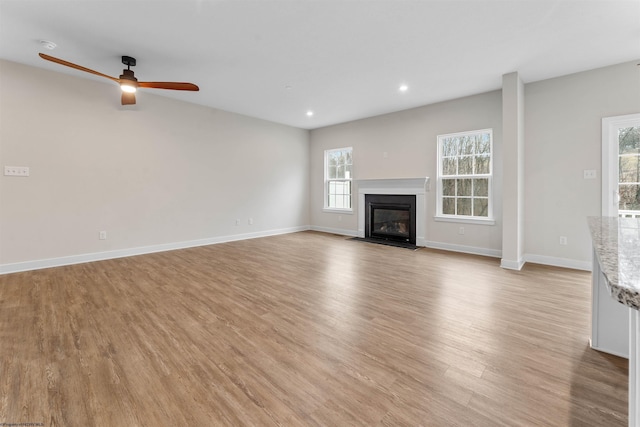 unfurnished living room with light wood finished floors, baseboards, a fireplace with flush hearth, ceiling fan, and recessed lighting