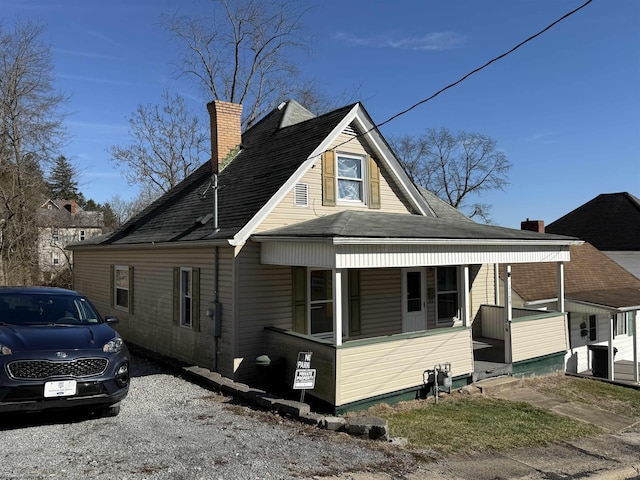 view of property exterior featuring a shingled roof, covered porch, and a chimney