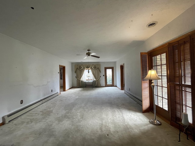 spare room featuring carpet, ceiling fan, a baseboard radiator, and visible vents