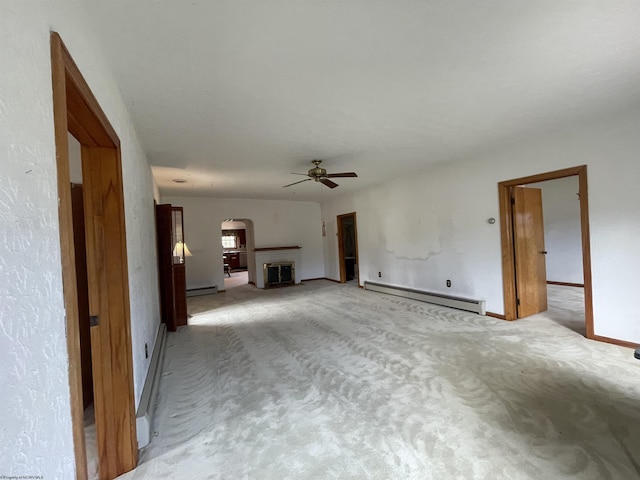 unfurnished living room with arched walkways, a fireplace, a baseboard heating unit, light carpet, and ceiling fan