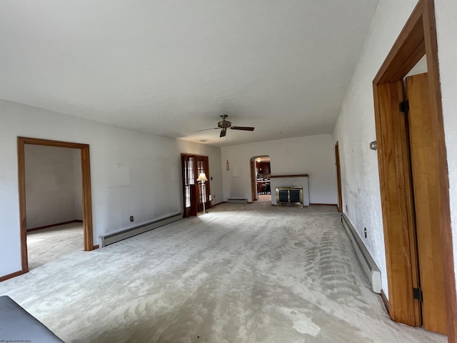 unfurnished living room with a baseboard heating unit, ceiling fan, light carpet, and a fireplace