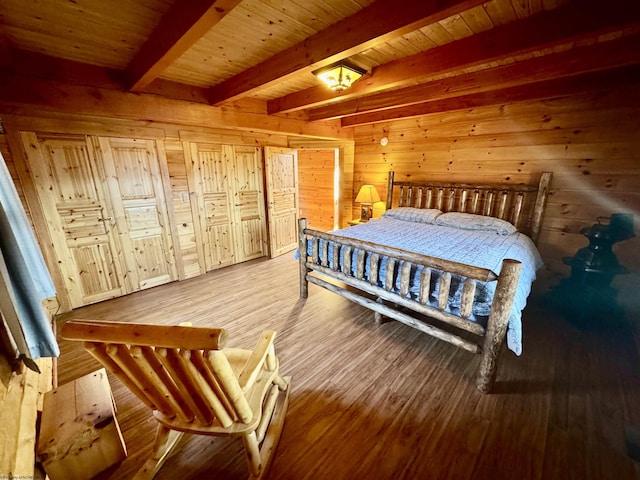 bedroom featuring beam ceiling, wooden walls, and wood finished floors