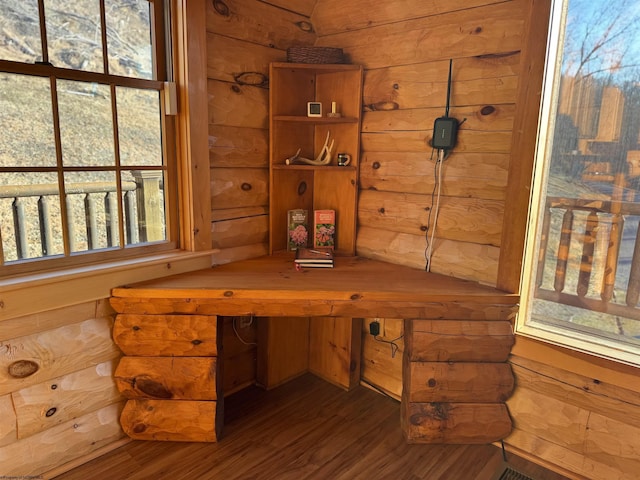 home office featuring wood walls, built in desk, and wood finished floors