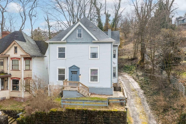 view of front of property with a shingled roof and a chimney