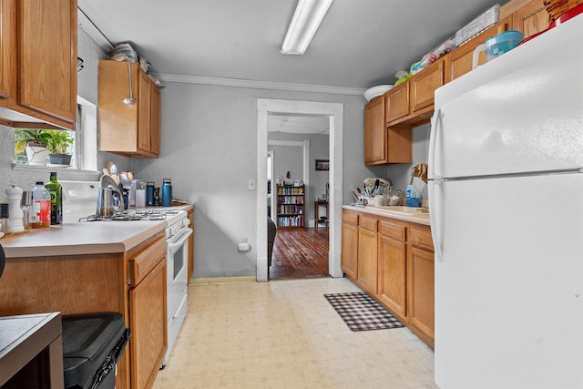 kitchen with white appliances, light countertops, light floors, brown cabinetry, and crown molding