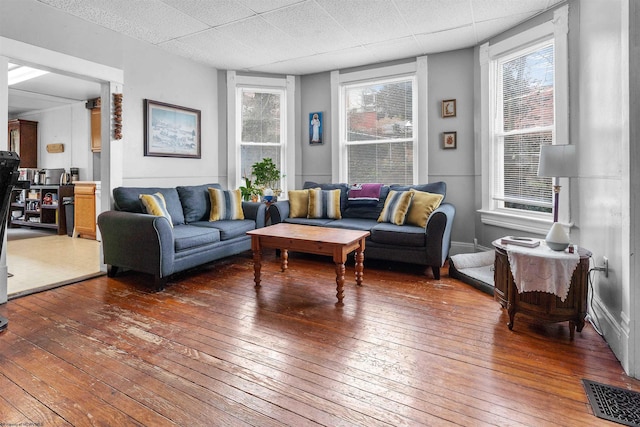 living area featuring a paneled ceiling, wood-type flooring, visible vents, and plenty of natural light