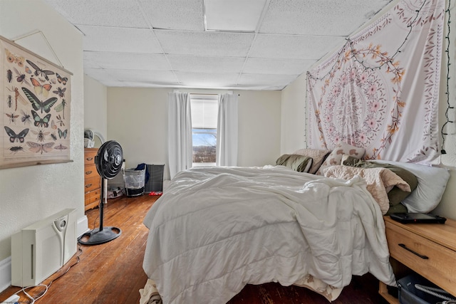 bedroom with a drop ceiling and wood finished floors