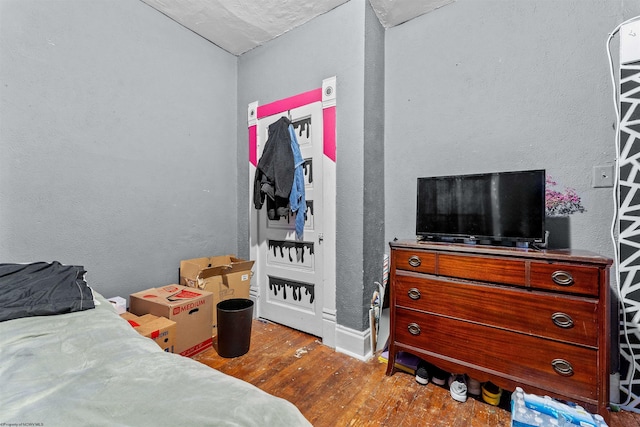 bedroom with wood finished floors and a textured wall