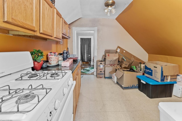 kitchen featuring lofted ceiling, light tile patterned floors, and white gas range