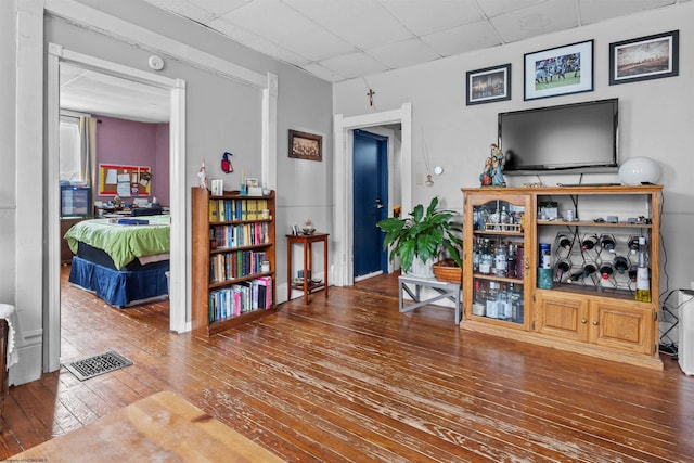 interior space featuring a drop ceiling, visible vents, and hardwood / wood-style floors