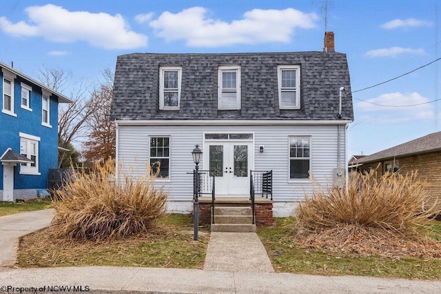 dutch colonial with roof with shingles, a chimney, and french doors