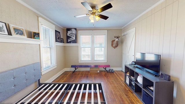 interior space featuring a textured ceiling, hardwood / wood-style flooring, a ceiling fan, baseboards, and crown molding