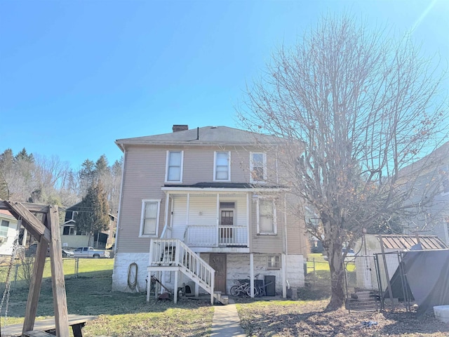 rear view of property with covered porch, fence, a chimney, and stairs