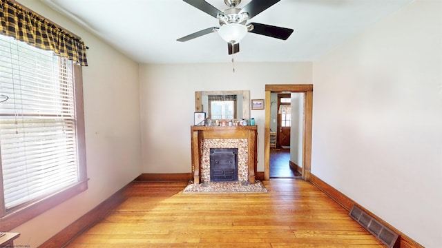 unfurnished living room featuring light wood-type flooring, a healthy amount of sunlight, visible vents, and baseboards