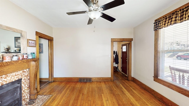 living area featuring a wealth of natural light, a tiled fireplace, wood-type flooring, and visible vents