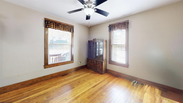 unfurnished room with baseboards, visible vents, ceiling fan, and light wood finished floors