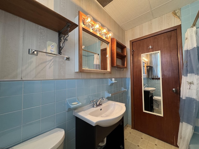 full bathroom with toilet, wallpapered walls, a shower with curtain, and wainscoting