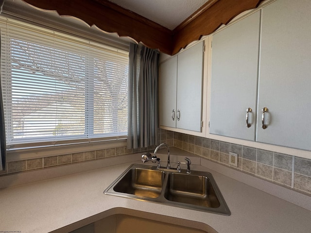 kitchen featuring light countertops, a sink, and white cabinetry