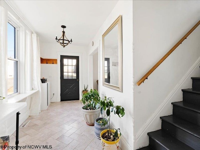 foyer entrance featuring stairs and a chandelier