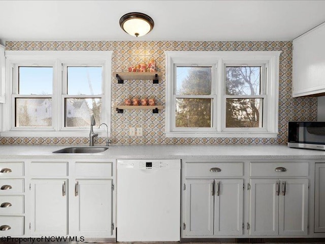 kitchen with light countertops, stainless steel microwave, backsplash, a sink, and dishwasher