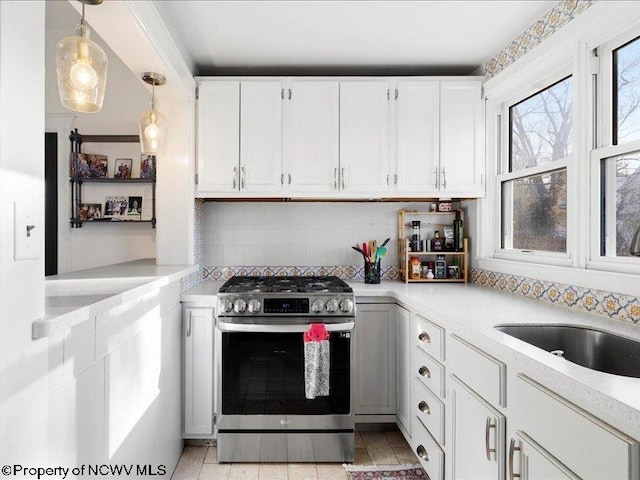 kitchen with light countertops, white cabinets, stainless steel range with gas stovetop, and backsplash