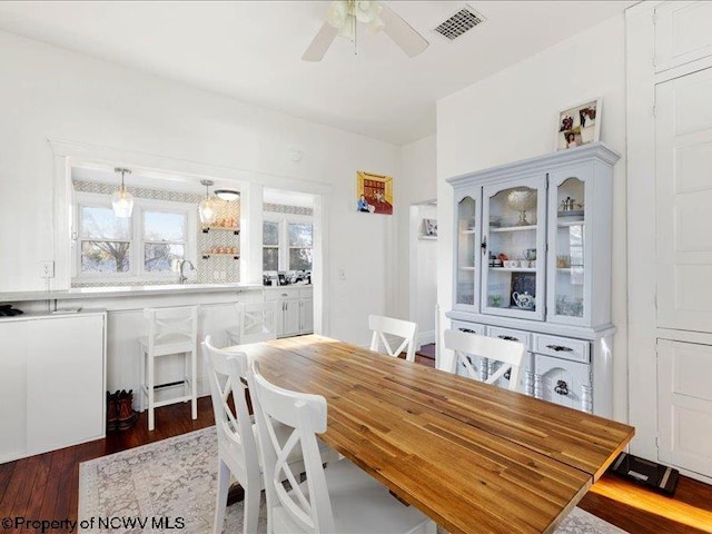 dining room featuring dark wood-style flooring, visible vents, and a ceiling fan