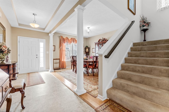 entrance foyer featuring ornate columns, baseboards, stairway, and a raised ceiling