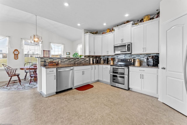 kitchen featuring stainless steel appliances, a peninsula, white cabinetry, and decorative backsplash