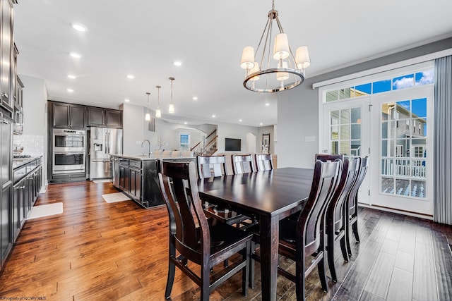 dining room with a chandelier, recessed lighting, dark wood-style flooring, and stairs