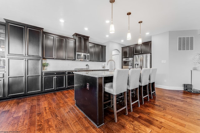 kitchen with dark wood-style floors, tasteful backsplash, visible vents, and stainless steel appliances