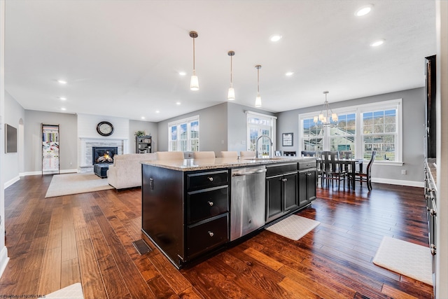 kitchen featuring baseboards, dishwasher, dark wood-style floors, dark cabinets, and a sink