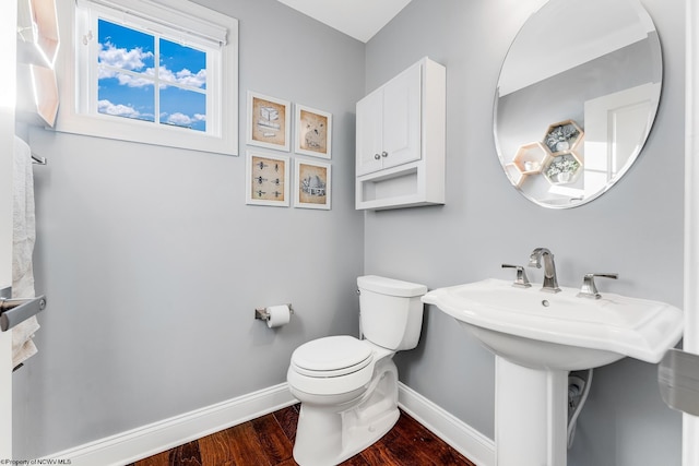 bathroom with toilet, baseboards, and wood finished floors