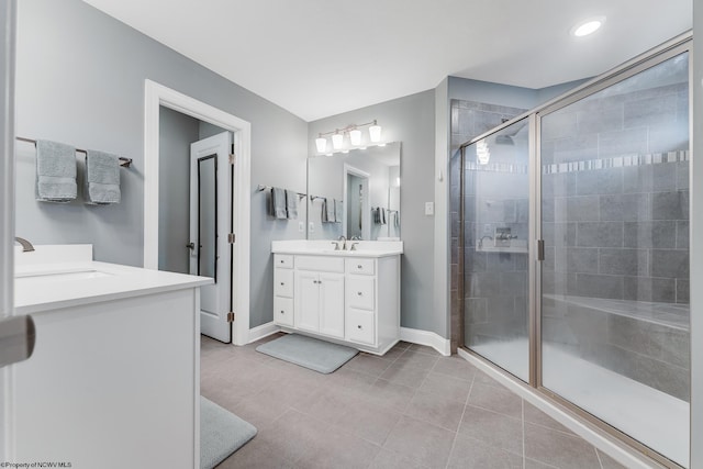 bathroom with a stall shower, baseboards, two vanities, and a sink