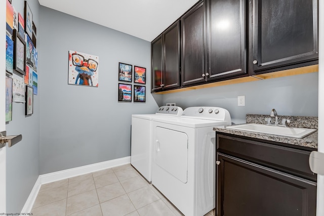 washroom featuring cabinet space, light tile patterned floors, baseboards, separate washer and dryer, and a sink