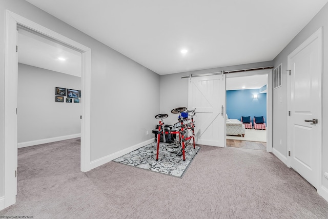 workout area with a barn door, carpet, visible vents, and baseboards